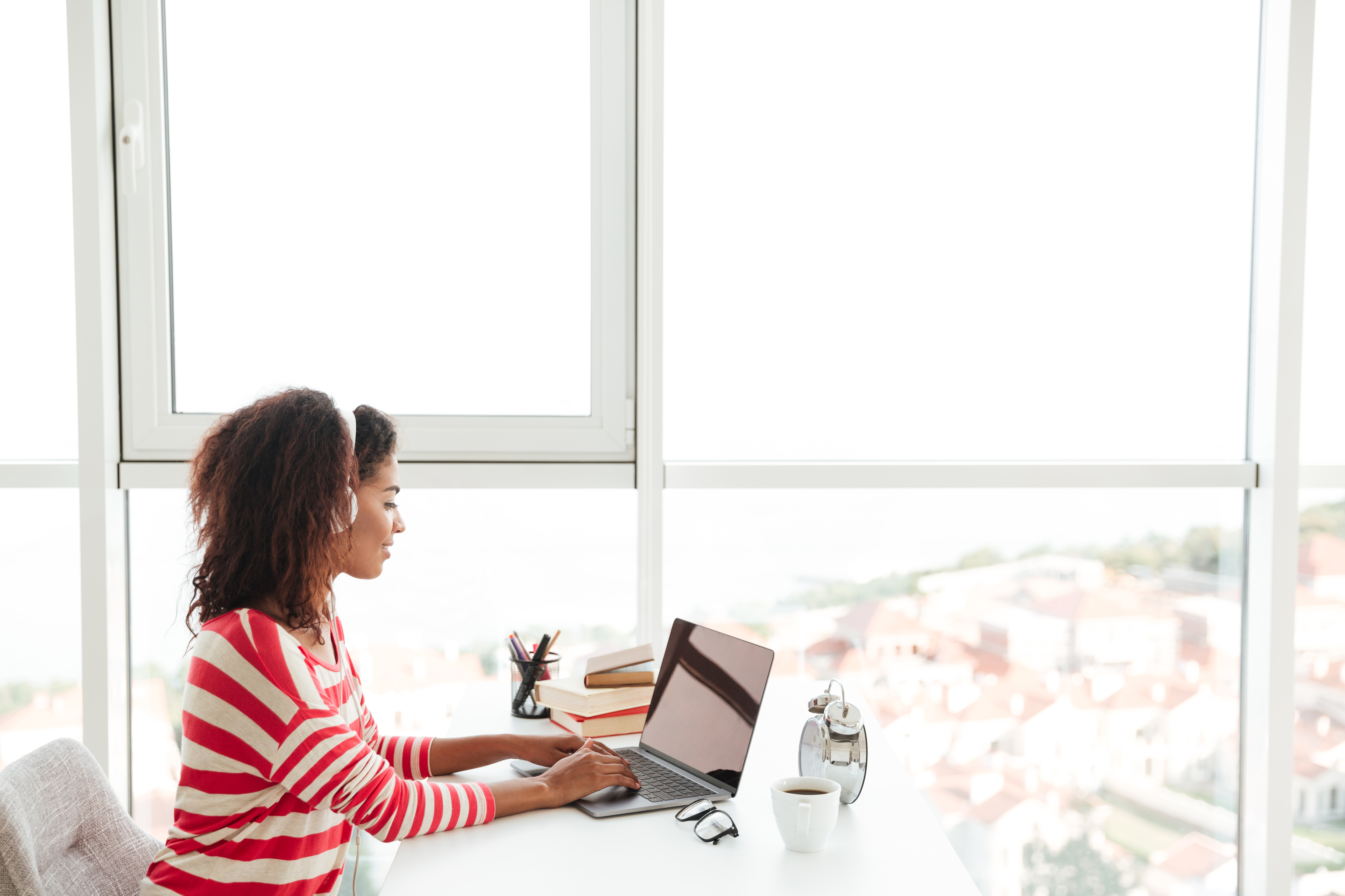 Young confident african woman in headphones working on laptop